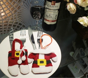 Detailed close-up of Santa suit cutlery holders with silverware on a white porcelain plate