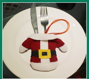 Close-up of Santa Claus outfit cutlery holder on white plate for Christmas table decor