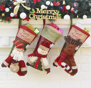 Three plush Christmas stockings with Santa, Snowman and Reindeer on a white fireplace