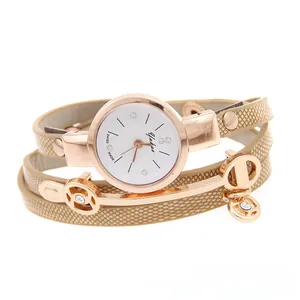 Detail of rose gold quartz watch with beige plaid wrap strap and charm pendant