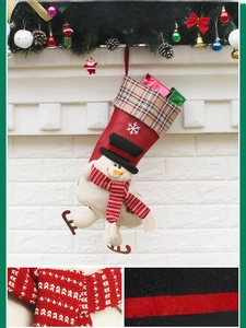 Détail d'une chaussette de Noël en toile rouge avec bonhomme de neige et motif écossais