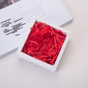 Macro detail of vibrant red shredded raffia paper filler in a white gift box
