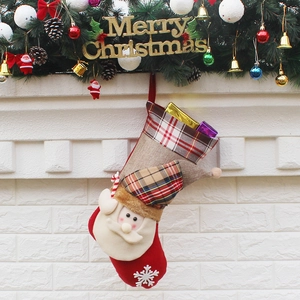 Classic red plaid Christmas stocking with Santa Claus hanging on fireplace mantel decor