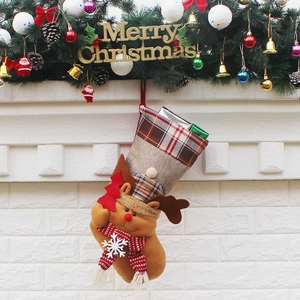 Brown reindeer Christmas stocking with plaid trim and gift box hanging on fireplace