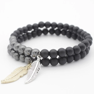 Detail of matte black and hematite beads featuring gold and silver feather charms