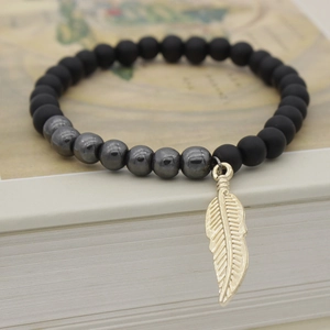 Matte black and hematite beaded bracelet with gold leaf pendant on a vintage book