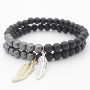 Detail of beaded bracelet with matte black agate, hematite, and gold/silver feathers