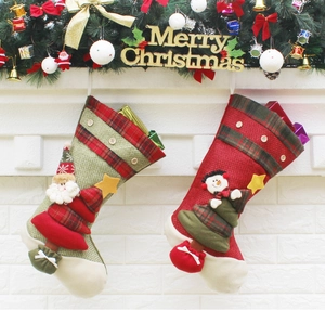 Classic red and green burlap Christmas stockings with Santa and snowman on a fireplace