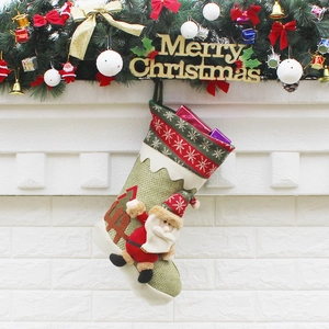 Green Christmas stocking with Santa Claus doll hanging on a festive decorated fireplace