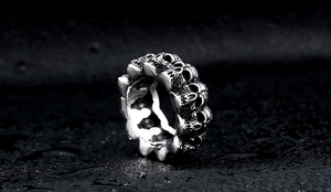 Macro shot of punk style silver stainless steel ring featuring continuous skulls pattern