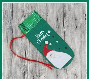Detail of green felt Christmas wine bottle cover with sequined Santa Claus embroidery