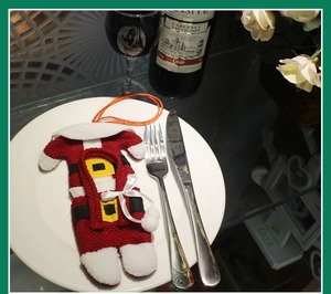 Mini Santa Claus suit cutlery holder on a white plate for Christmas table decoration