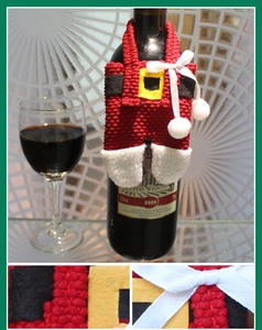 Detail of red knitted Santa pants wine bottle cover with white pom-poms and belt
