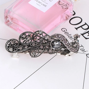 Close-up of vintage peacock hair clip with grey crystals and silver alloy relief