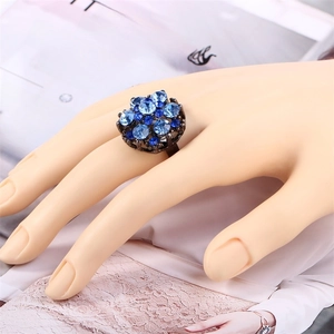 Close-up of blue crystal flower ring on model hand with dark alloy base and rhinestones