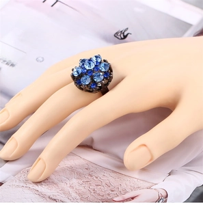 Detailed top view of a vintage flower ring with blue crystals on a dark alloy band