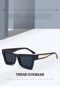 Detail of square black sunglasses with golden metal accents and gray lenses