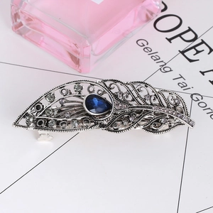 Detail of vintage peacock feather hair clip with blue gemstone and rhinestones