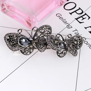 Close-up of vintage silver butterfly hair clip with grey gemstones and purple rhinestones