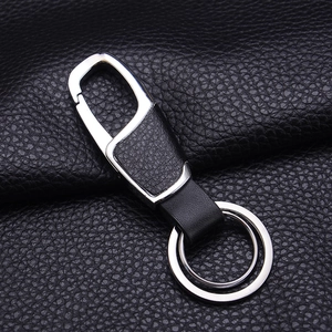 Detailed close-up of a premium black leather and silver metal keychain on leather surface