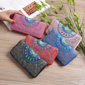 Dettaglio di cinque portafogli ricamati etnici con motivi floreali colorati e texture