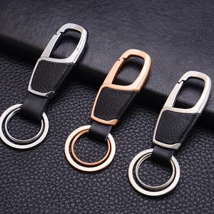 Detail of three metal and leather car keychains in gunmetal, rose gold, and silver finishes