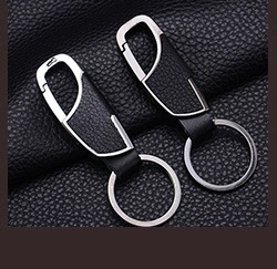 Detail view of two faux leather and silver metal keychains on a dark textured background