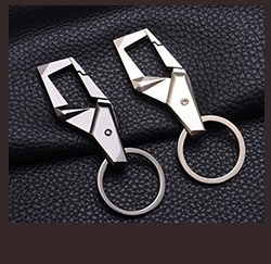 Detail of square geometric metal keychains in dark grey and silver on leather background