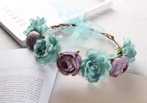 Close-up of bohemian floral wreath featuring light blue and purple silk flowers with ribbons