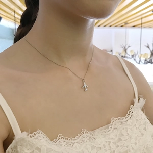 Detail shot of a minimalist silver aircraft pendant necklace on a female model