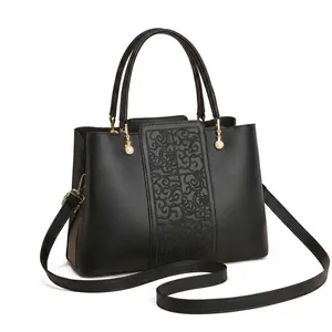 Close-up of black leather handbag with golden hardware and elegant pearl pendant detail