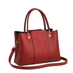 Close-up of wine red leather handbag with embossed cloud pattern and gold chain