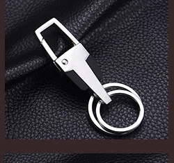 Macro shot of polished metal spring clip and black faux leather double ring keychain