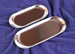 Overhead view of two oval stainless steel trays on a blue pleated fabric background