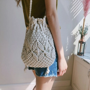 Detail of bohemian cream crochet mesh bag with wooden beads and woven texture