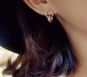 Detail of rose gold stud earrings with Roman numerals and shimmering crystal stones
