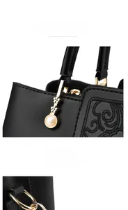 Detail of vintage embroidery on black tote bag with gold hardware and pearl charm