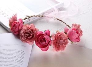 Detail of pink silk roses on a floral crown with a brown branch base and ribbon
