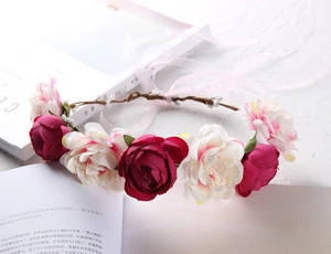 Macro view of realistic deep red and cream silk roses on a bohemian floral headband