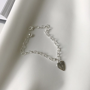 Detail of S925 sterling silver heart pendant bracelet with vintage etched sun texture