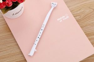 Close-up of white cat-themed gel pen with paw prints on a pink notebook