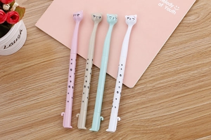 Close-up of four cute cartoon cat gel pens in pastel colors on a wooden desk