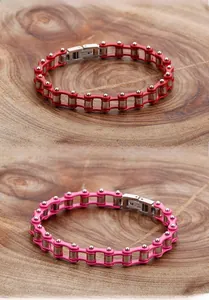 Detailed close-up of pink and red motorcycle chain bracelets on a rustic wooden background