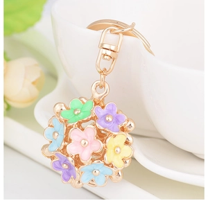 Detail showing colorful enamel daisy flowers on a hollow sphere gold alloy keychain