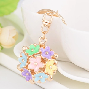 Colorful floral enamel keychain with macaron flower petals and golden metal clasp on a cup