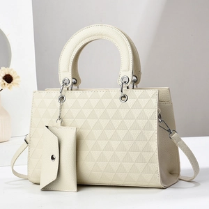 Detail view of cream white tote bag with geometric triangle pattern and mini pouch charm
