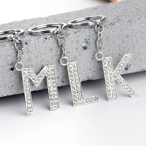 Detail of silver alloy M, L, K letter keychains with shimmering white rhinestones