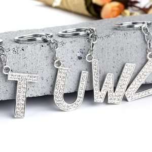 Close-up of silver alphabet T, U, W, Z keychains encrusted with sparkling rhinestones