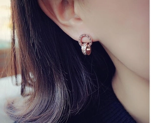 Detail of rose gold double ring earrings with Roman numerals and pavé micro diamonds