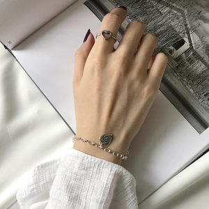 Close-up of vintage silver heart ring and pendant bracelet set on a book page